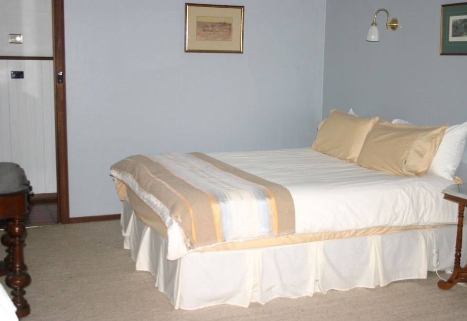 a neatly made bed with a white and gold striped blanket is in a room with blue walls at Riverhouse at Howqua Dale
