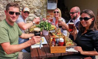 a group of people are sitting at a wooden table , toasting with beer and having fun at The Bugle Coaching Inn