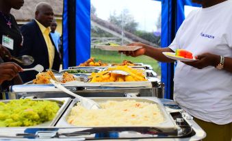 a man is serving food from a buffet , while another person looks on , in a tent - like setting at Lalanasi Lodge