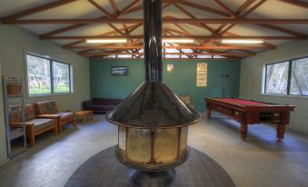 a room with a large wood - burning stove and a pool table , as well as several benches at Kosciuszko Tourist Park