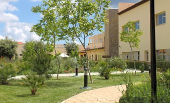 a small courtyard surrounded by grass and trees , with a building in the background at Hotel Sierra Luz