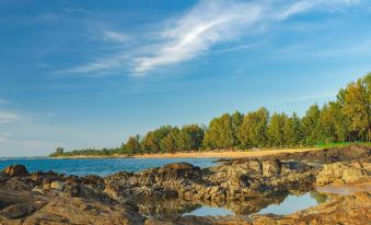a serene beach scene with a body of water surrounded by rocks and trees , creating a picturesque landscape at La Vela Khao Lak