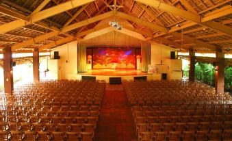an empty auditorium with rows of wooden chairs and a stage , under a thatched roof at Fiesta Resort All Inclusive Central Pacific - Costa Rica
