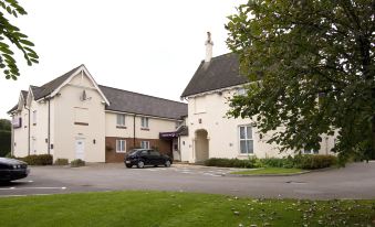 a car is parked in front of a white building with a gray roof , surrounded by trees at Taunton Ruishton (M5, J25)