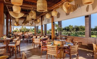 an outdoor restaurant with wooden tables and chairs , hanging lanterns , and a view of the outdoors at NissiBlu Beach Resort