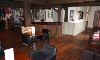 a bar area with several chairs and tables , as well as a painting on the wall at The Selsey Arms