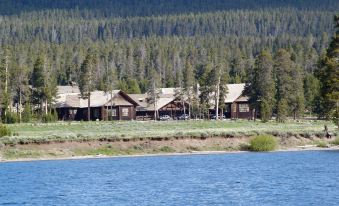 a group of small wooden cabins situated on the shore of a lake , with mountains in the background at Lake Lodge