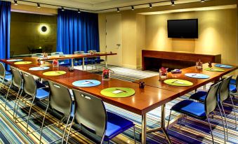 a conference room with a long table , chairs , and a television mounted on the wall at Aloft Leawood-Overland Park