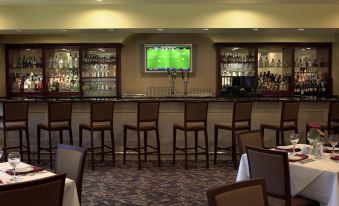 a dining room with tables and chairs set up for a restaurant , along with a bar in the background at DoubleTree by Hilton Claremont