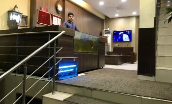 a man standing in a hotel lobby , wearing a suit and tie , while a television is on display at Hotel India