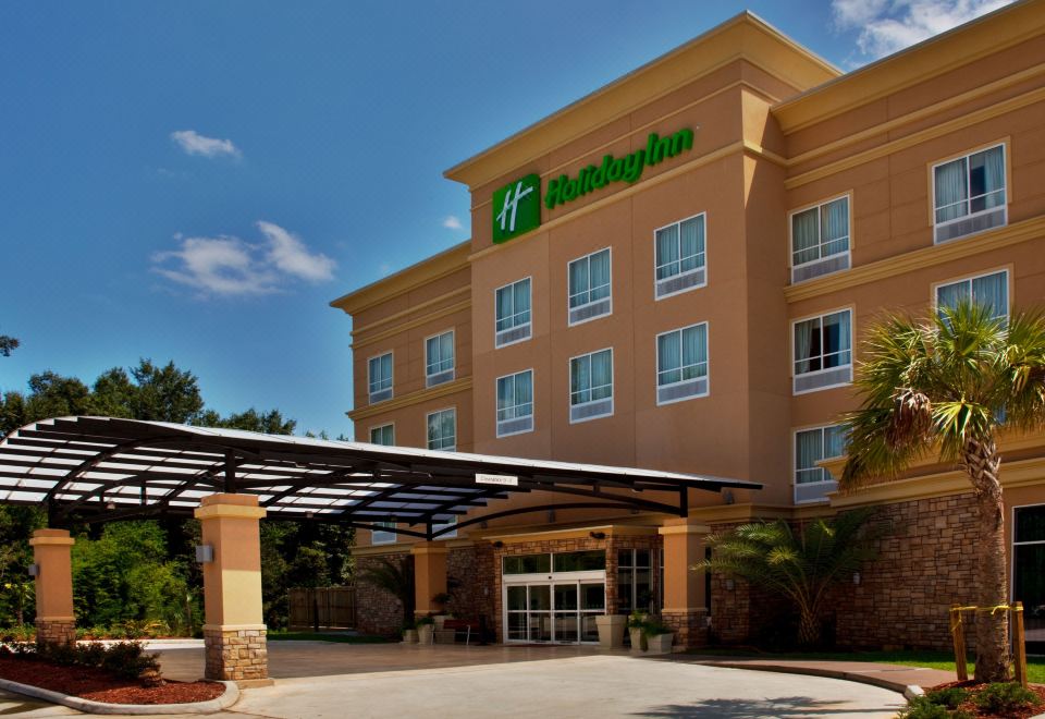 a holiday inn hotel with its large sign and blue roof , under a clear blue sky at Holiday Inn Hammond