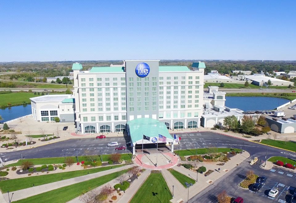 an aerial view of a large hotel with a blue logo on the front , surrounded by trees and grass at Isle Casino Hotel Waterloo