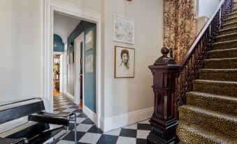 a staircase with a black and white checkered floor leads to an entrance with a framed picture on the wall at Stowaway