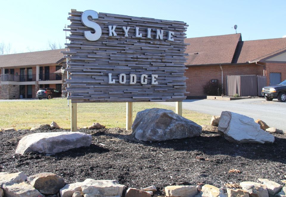 "a large wooden sign with the words "" skyline lodge "" written on it , surrounded by rocks and grass" at Skyline Lodge
