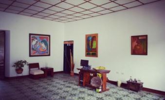 a room with a desk , computer , and paintings on the walls and floor , possibly in a hotel or office setting at Hotel San Cristobal