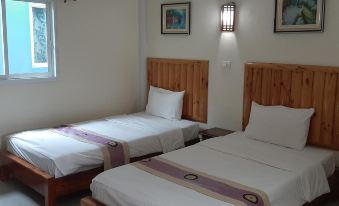 There are two single-sized rooms with wood trim and white sheets, each containing a bed or beds at Punyaporn Resort