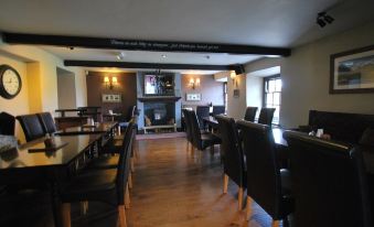 a large room with wooden floors , high ceilings , and black chairs around a wooden table at The Punchbowl Hotel