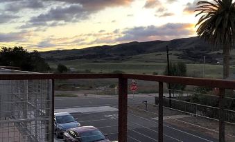 a view from a balcony overlooking a parking lot with cars and palm trees during sunset at Wine Stone Inn