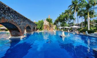 a large outdoor swimming pool surrounded by palm trees , with several people enjoying their time in the water at Hotel Hacienda Vista Hermosa