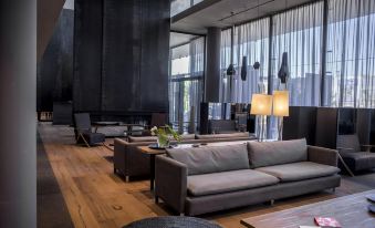 a modern living room with gray couches and chairs arranged around a large flat - screen tv at Kos Pilar Hotel