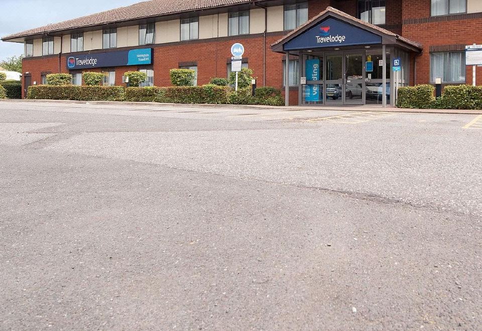 "a large , brick building with a blue sign that says "" the express "" is situated on a street" at Travelodge Nottingham Trowell M1