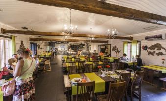 a large , well - lit restaurant with wooden beams and numerous dining tables filled with people enjoying their meals at Ranua Resort Holiday Villas