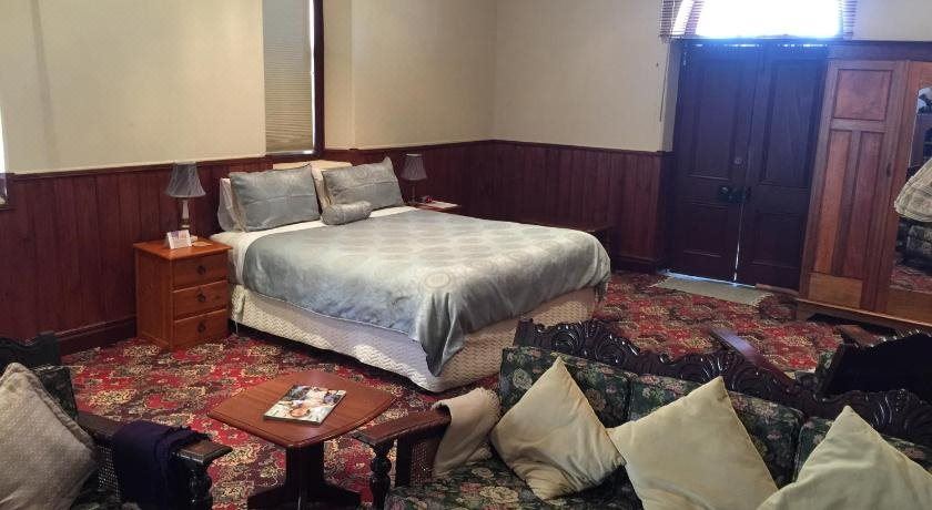 a bedroom with a large bed , two couches , and a door leading to another room at Clare Valley Cabins