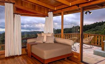 a wooden cabin with a large window offering a view of the mountains , and a couch with pillows in front of it at Hotel Belmar