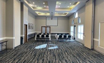 a large conference room with multiple chairs arranged in rows and a projector screen mounted on the wall at AmericInn by Wyndham Valley City Conference Center