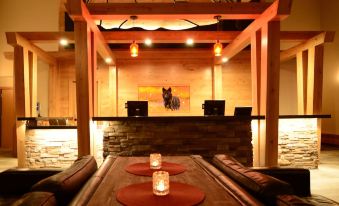 a room with a wooden table and chairs , surrounded by candles and a fireplace , is illuminated by the setting sun at Banff Rocky Mountain Resort