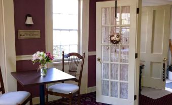 a dining room with a table and chairs , as well as a door leading to a kitchen at Spring Hill Inn