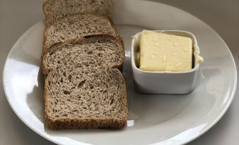 a white plate with slices of bread and a small bowl of butter on a table at EastWest Hospitality