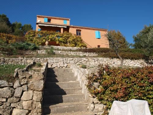 a stone staircase leading up to a two - story house with a blue roof , surrounded by greenery at La Roque