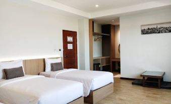 a modern hotel room with two beds , white bedding , and wooden flooring , as well as a kitchen area at Koco Hotel