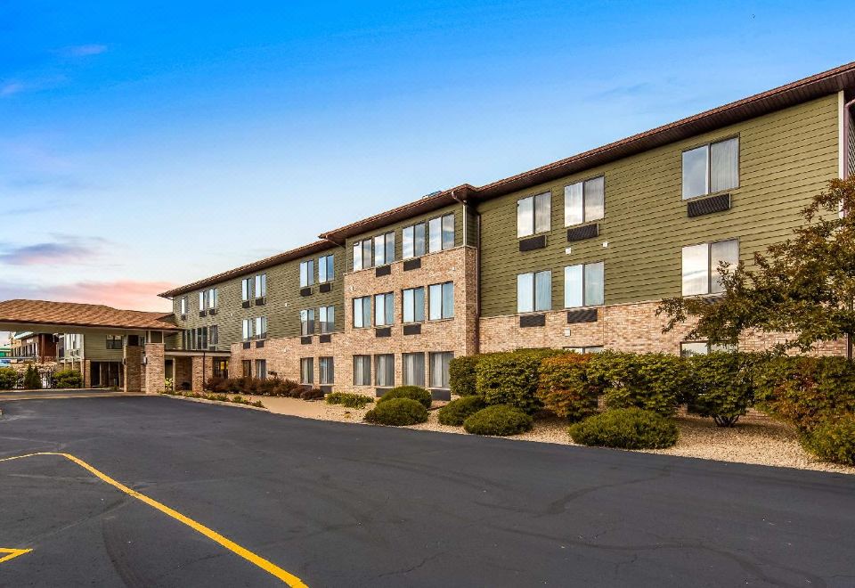 a three - story building with a green roof and stone accents , surrounded by trees and bushes at Best Western Park Oasis Inn