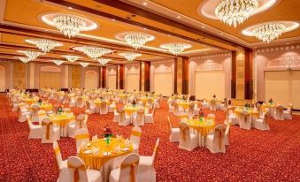 a large banquet hall with multiple round tables set up for a formal event , surrounded by white chairs and chandeliers at Resort Rio