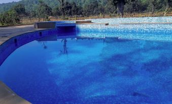 a large , blue pool with a diving board and several jets is surrounded by trees at Wildflower Resort
