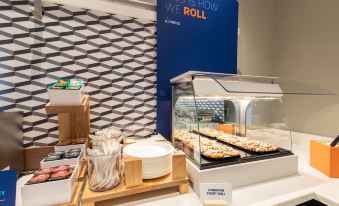 "a display case with plates and bowls of food , next to a sign that says "" this is how we roll .""." at Holiday Inn Express Newington - Hartford