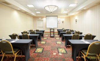 a conference room with rows of tables and chairs , a projector screen at the front , and a large chandelier hanging from the ceiling at Hilton Garden Inn Casper