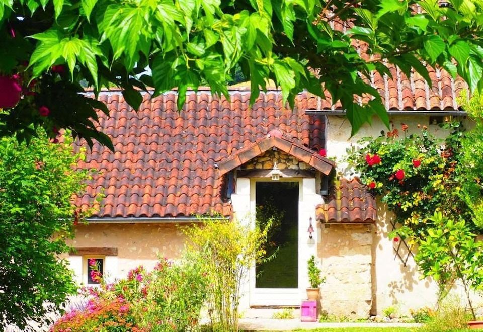 a house with a red tile roof and a white door is surrounded by greenery at La Belle Verte