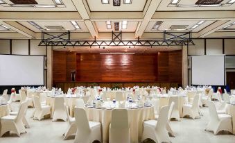 a large banquet hall with multiple round tables and chairs arranged for a formal event at Novotel Bukittinggi