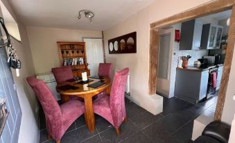 a dining area with a round table and four chairs , as well as a kitchen in the background at Myrtle Cottage