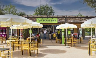 a small outdoor dining area with yellow tables and chairs , surrounded by a pool bar at Hu Montescudaio Village