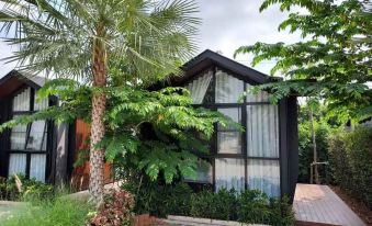 a small house with a window and a tree in front of it , surrounded by greenery at The Sept Korat