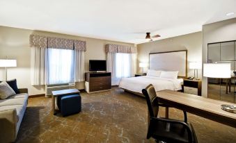 a spacious bedroom with a large bed , desk , and chair , as well as a window with curtains at Homewood Suites by Hilton Dover