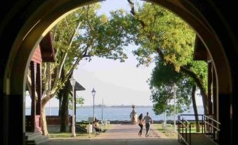 a group of people walking on a sidewalk near a body of water , possibly a lake or a river at Apartments Light