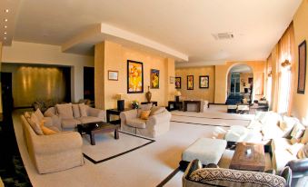 a spacious living room with multiple couches , chairs , and ottomans arranged around a dining table at Htop Caleta Palace #HtopBliss