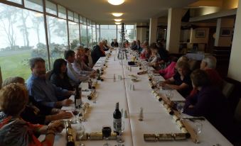 a group of people are sitting at a long table with wine glasses and bottles at Lufra Hotel and Apartments