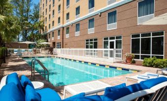 an outdoor swimming pool surrounded by a hotel , with several lounge chairs placed around the pool area at Hampton Inn Hallandale Beach-Aventura