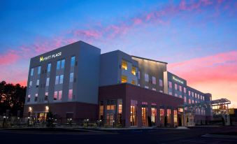 a large building with a large sign on the side and windows is shown at dusk at Hyatt Place Augusta